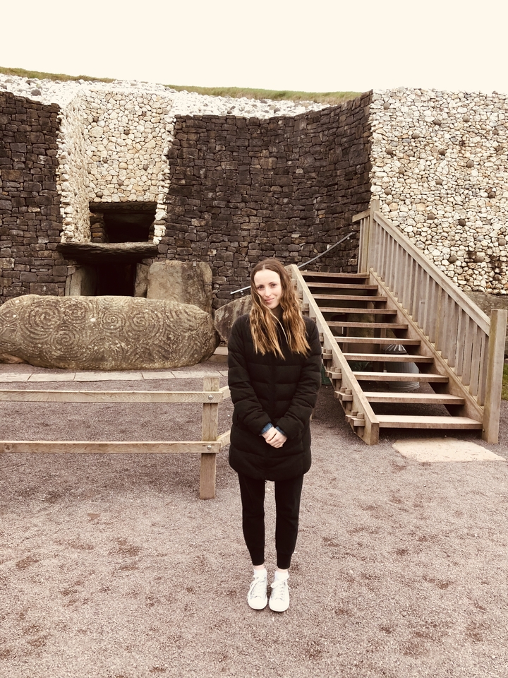 Une personne debout devant un monument de pierre ancien avec des motifs sculptés.