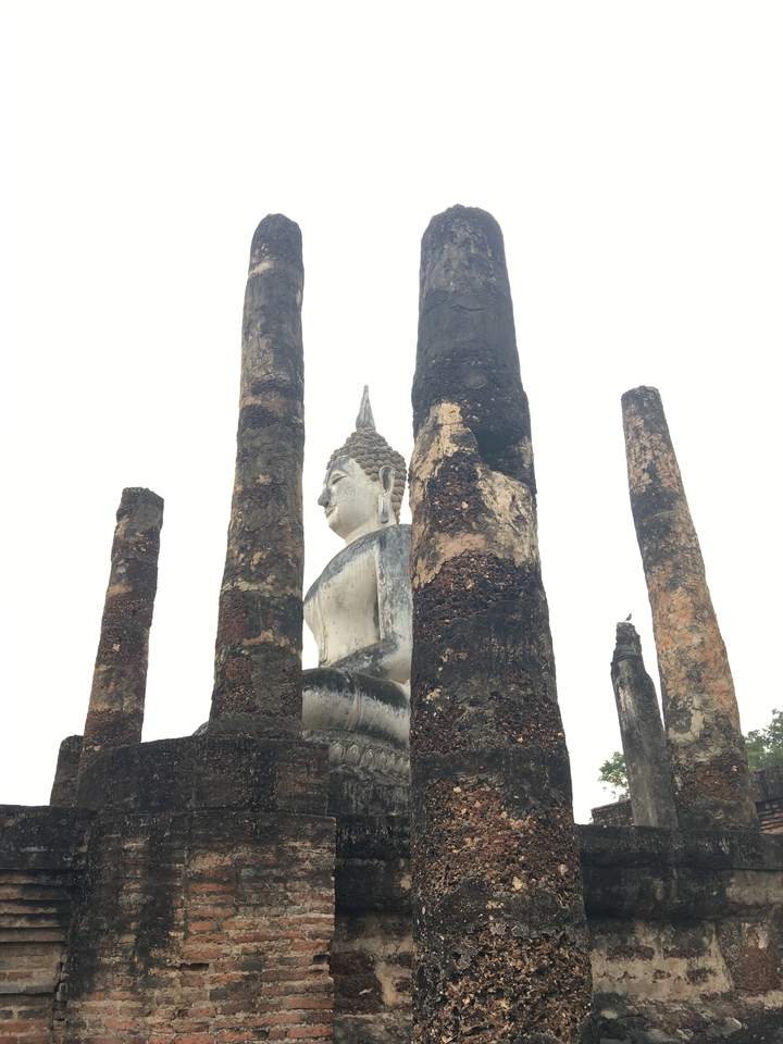 Statue de Bouddha parmi de hautes colonnes.