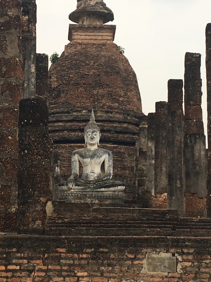 Statue de Bouddha assis avec des piliers anciens.