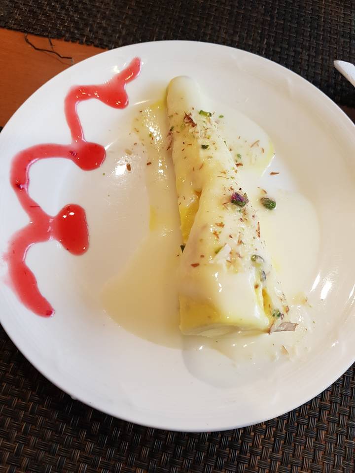 Dessert indien dans une assiette avec une sauce décorative.