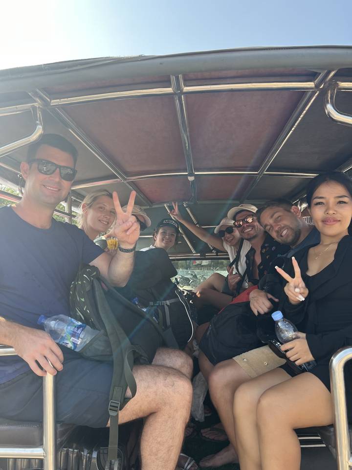 Groupe de touristes dans un véhicule ouvert, posant pour une photo de groupe.