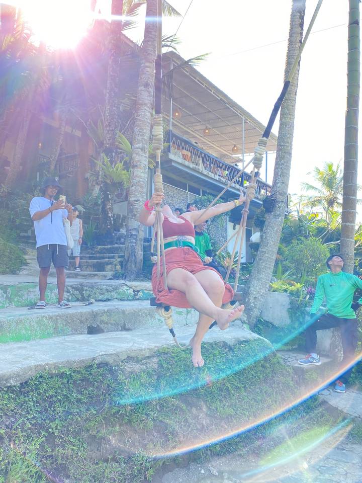 Deux personnes sur une balançoire avec un reflet de soleil visible.