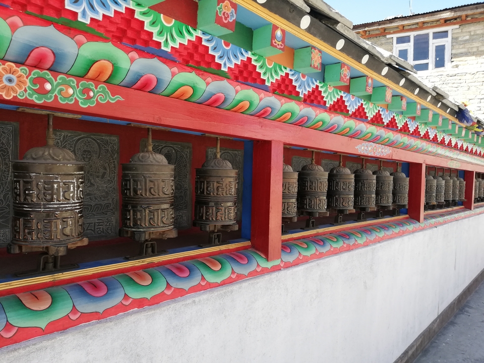 Moulins à prières colorés le long d'un mur dans un monastère.