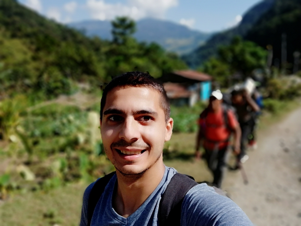 Personne souriante en randonnée avec un arrière-plan flou.