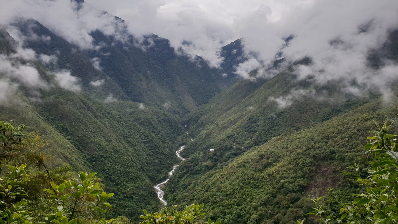Rivière coulant à travers une vallée verdoyante entourée de montagnes.