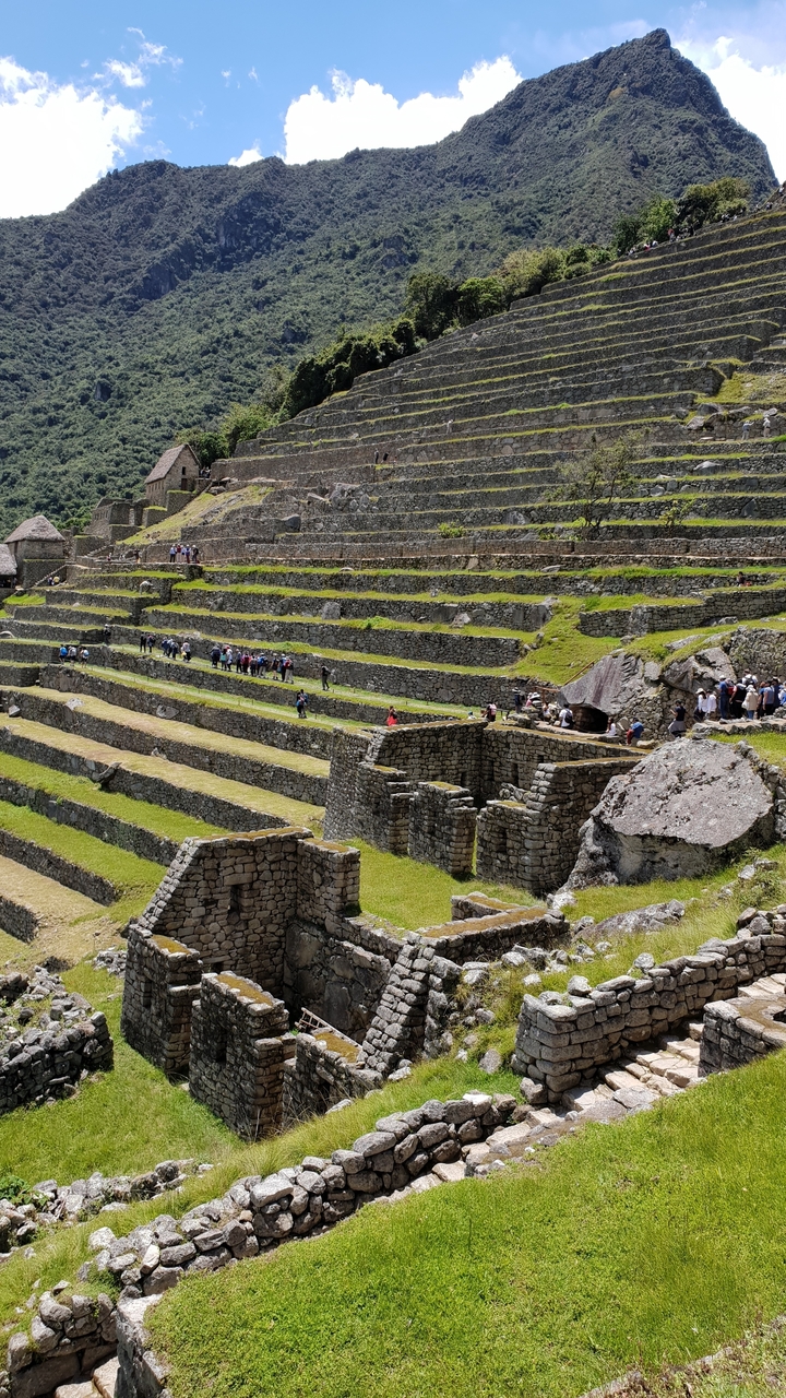 Des touristes explorant d'anciennes structures de pierre en terrasses.