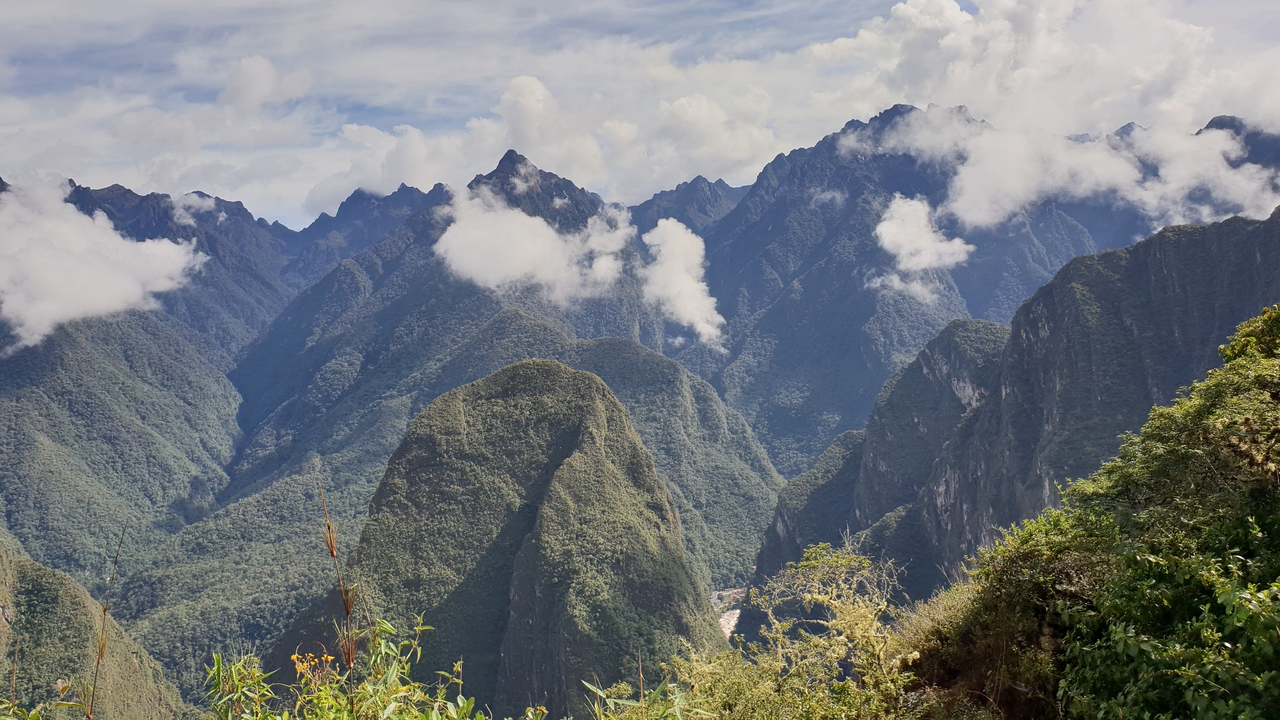 Vue panoramique de sommets montagneux avec des nuages sous la lumière du soleil.