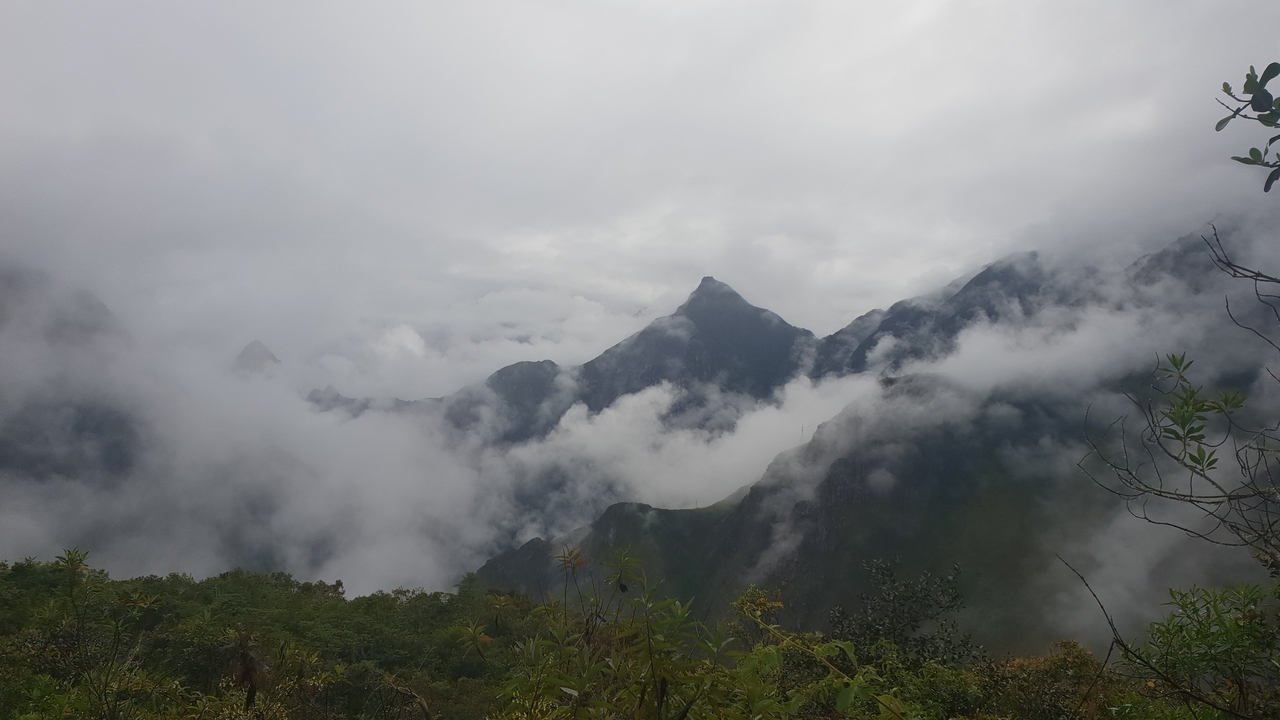 Paysage de montagne brumeuse avec des nuages enveloppant les sommets.