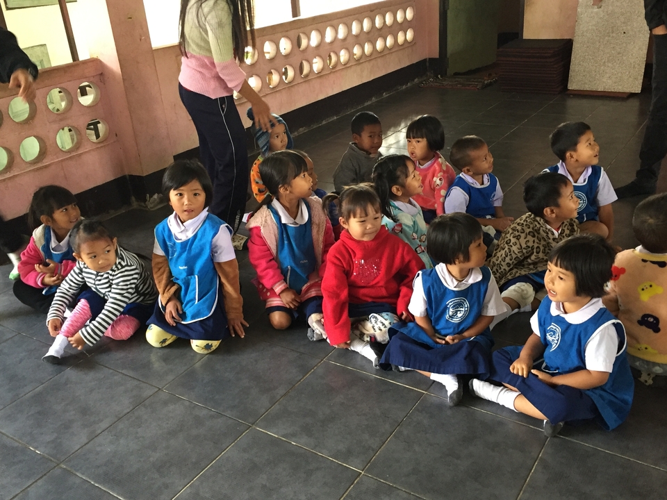 Un groupe d'enfants assis à l'intérieur en vêtements colorés.