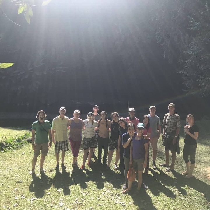 Groupe de personnes debout dans une clairière ensoleillée.