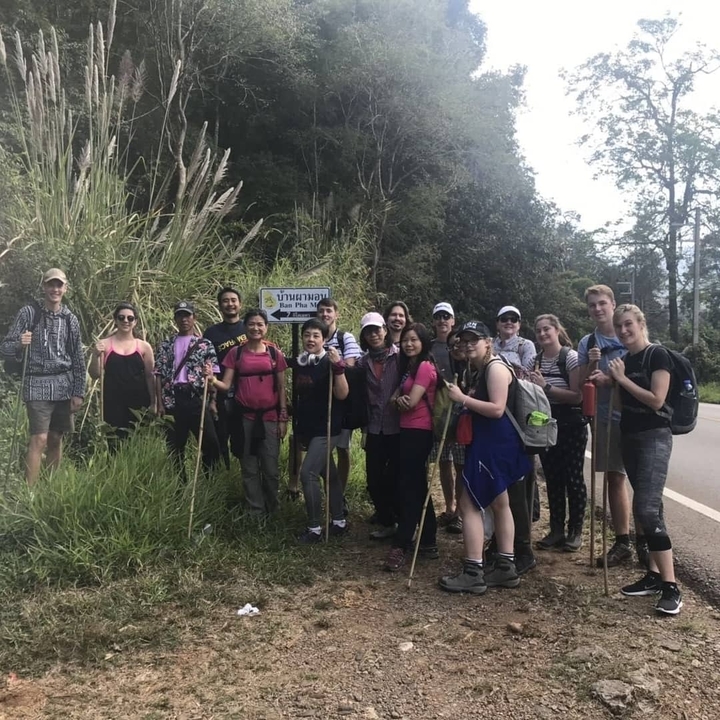 Groupe de randonneurs posant à côté d'un panneau routier.