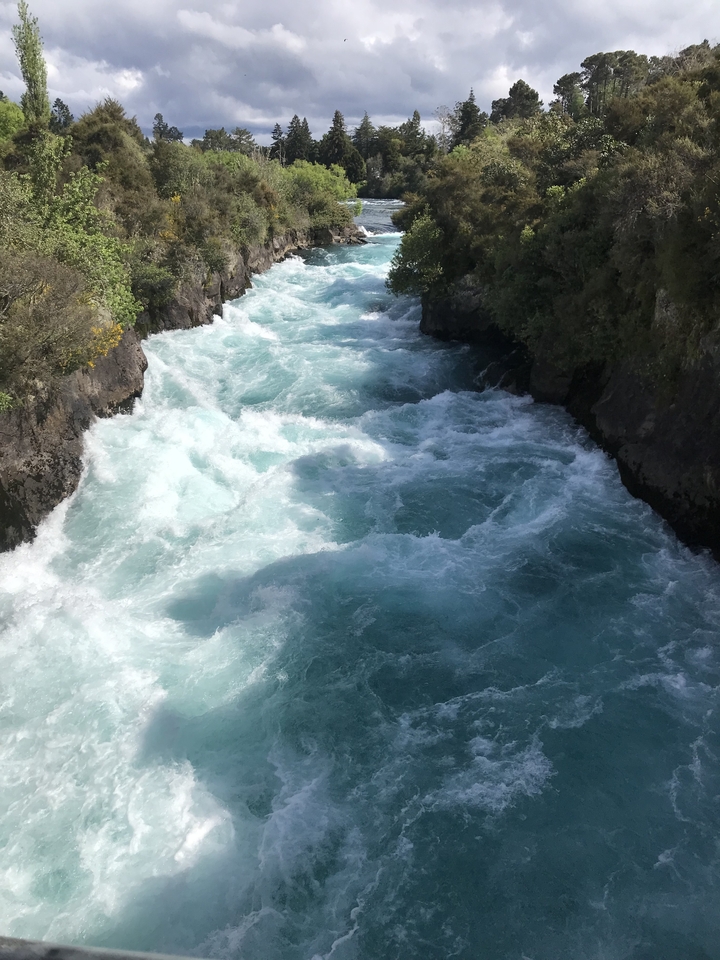Here's the French translation:
**Eau de rivière tumultueuse avec des rochers par une journée ensoleillée.**
Alternative translation:
**Rivière au courant rapide avec des rochers sous un jour ensoleillé.**