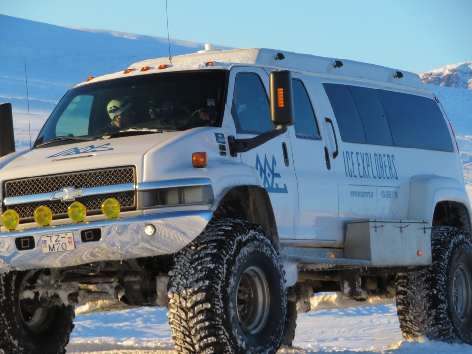Un gros véhicule avec des personnes à l'intérieur équipé pour le terrain enneigé.