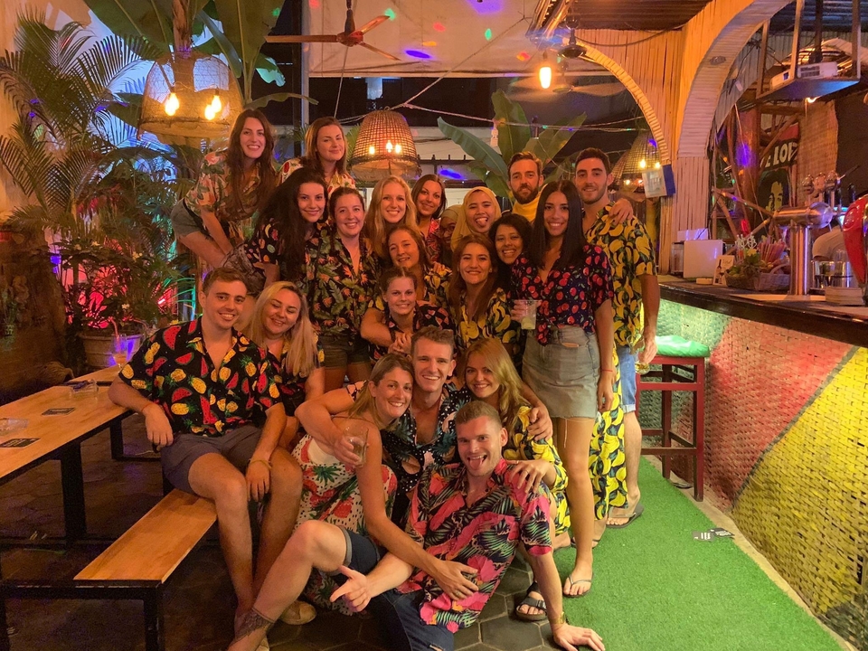 Groupe de personnes dans un bar portant des chemises colorées posant pour une photo.