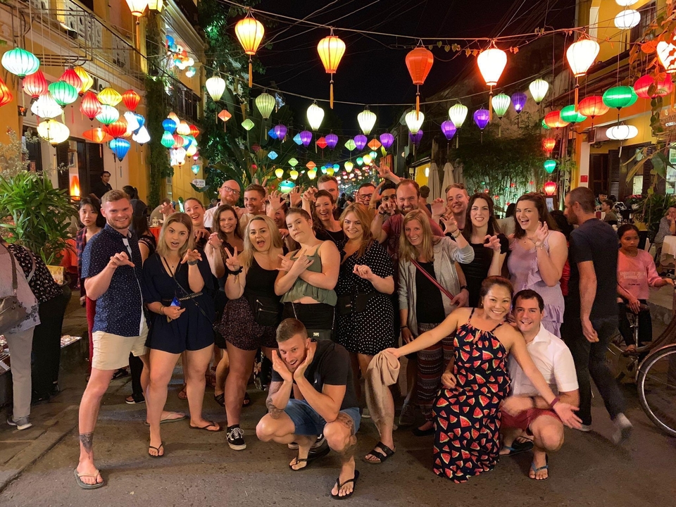 Grand groupe de personnes posant sous des lanternes colorées la nuit.
