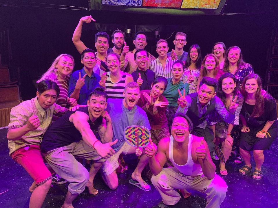 Grand groupe de personnes posant joyeusement sur scène.