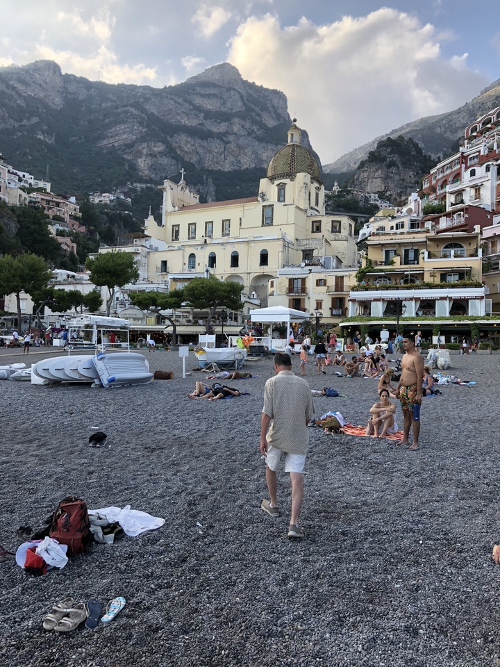 Paysage de front de mer avec des gens se détendant devant des bâtiments aux couleurs pastel.