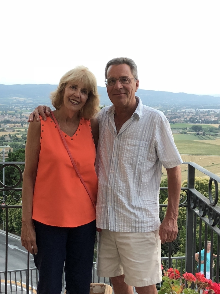 Deux personnes debout devant un paysage pittoresque avec des bâtiments au loin.
