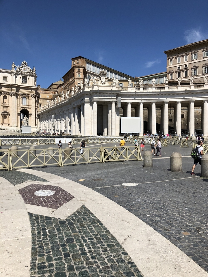 Des gens marchant devant une place classique avec des colonnes.