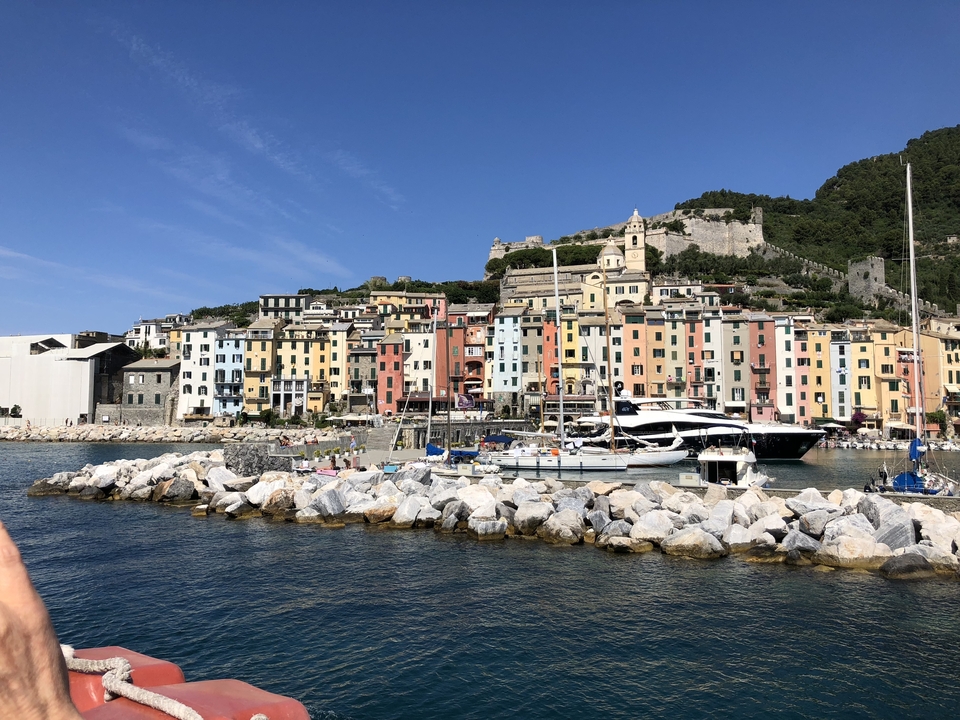 Ville côtière colorée avec des bateaux et un front de mer rocheux.
