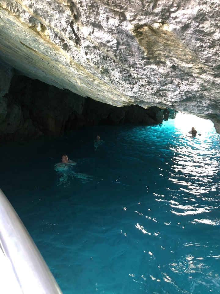 Des gens qui nagent dans une grotte avec de l'eau bleue.