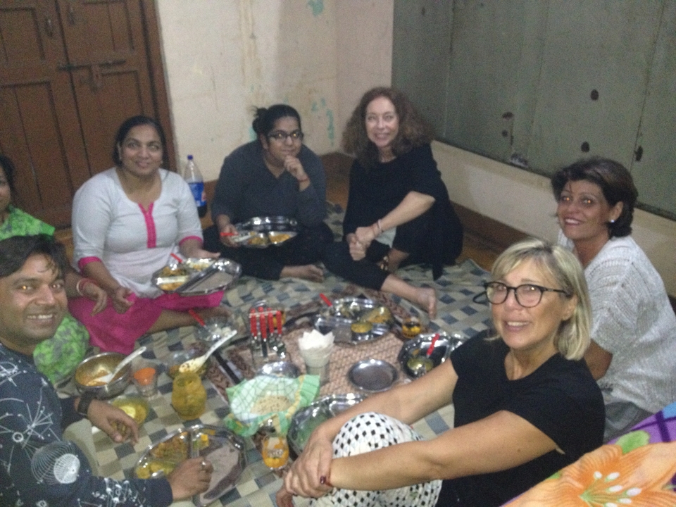 Groupe de personnes assises par terre en train de prendre un repas ensemble.