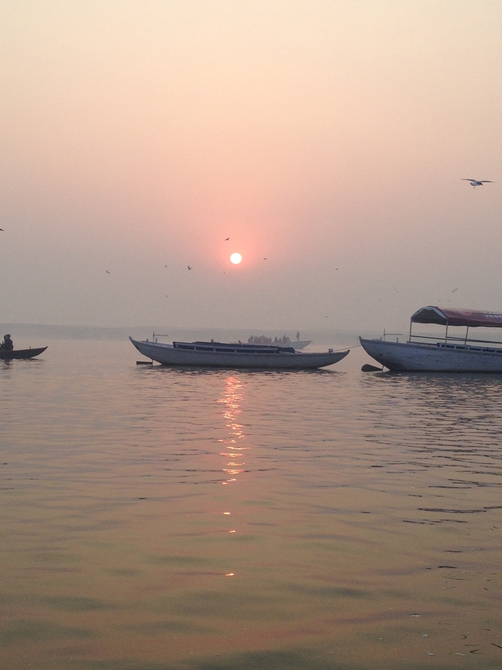 Bateaux sur une eau calme au coucher du soleil avec un ciel orange.