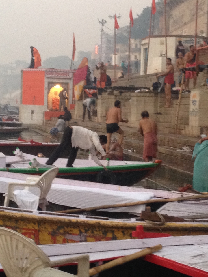 Des personnes effectuant des rituels religieux au bord de la rivière avec des bateaux.