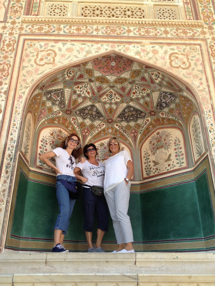 Trois femmes posant à l'intérieur d'une arche aux motifs décoratifs.