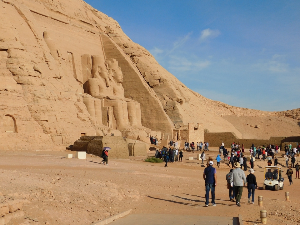 Des touristes visitant une grande statue de roche ancienne sur un site historique.