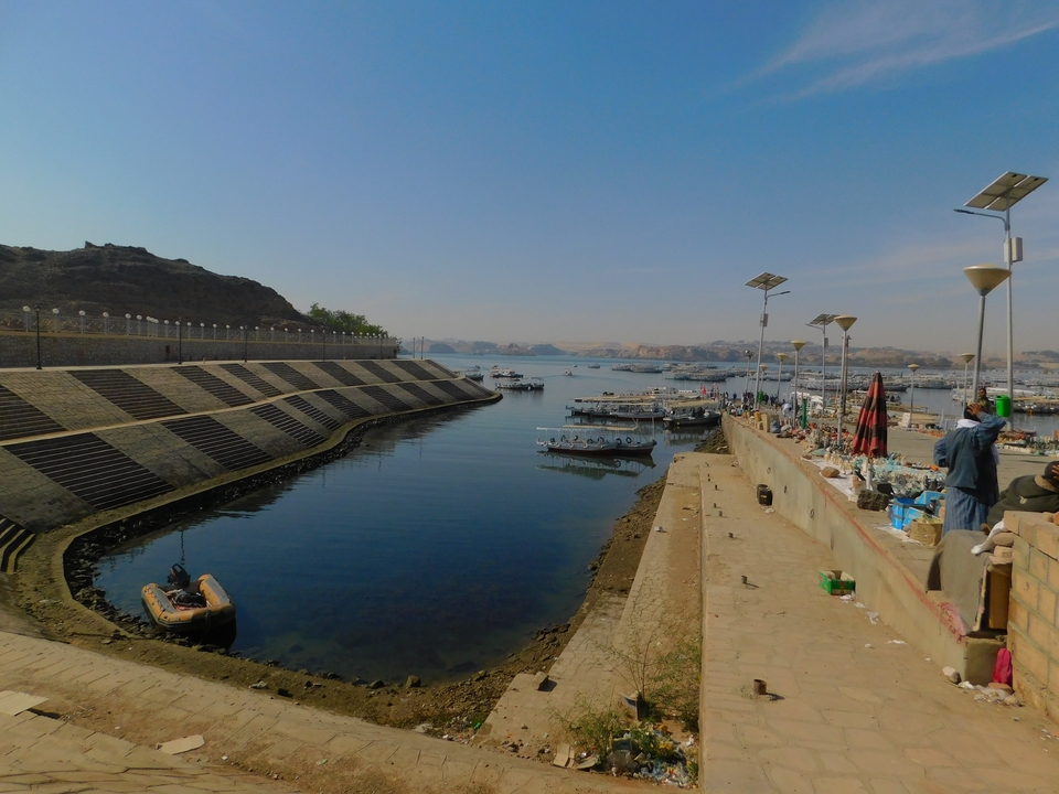 Bateaux amarrés à un front de mer avec des quais en pierre et des gens qui marchent.