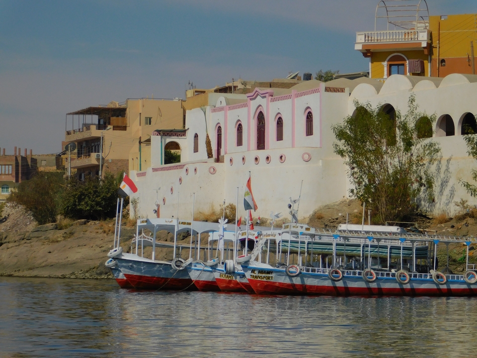Des bateaux colorés amarrés le long de bâtiments égyptiens traditionnels au bord du Nil.