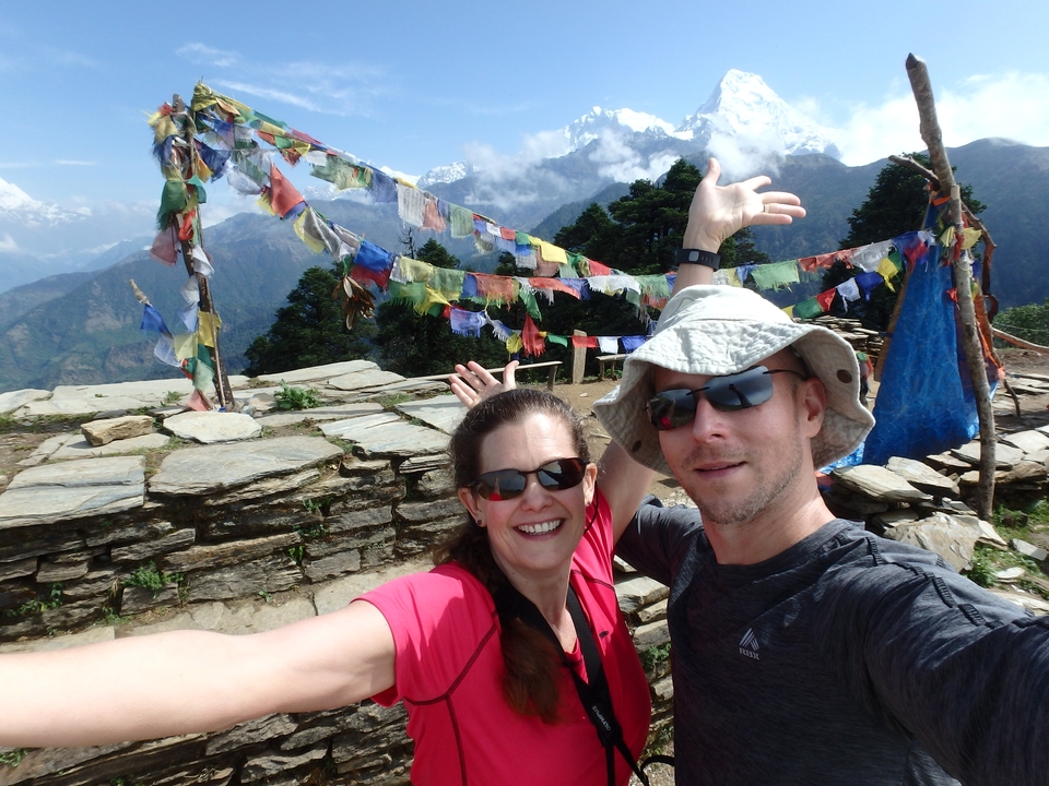 Couple posant à un point de vue avec des drapeaux de prière et des montagnes.