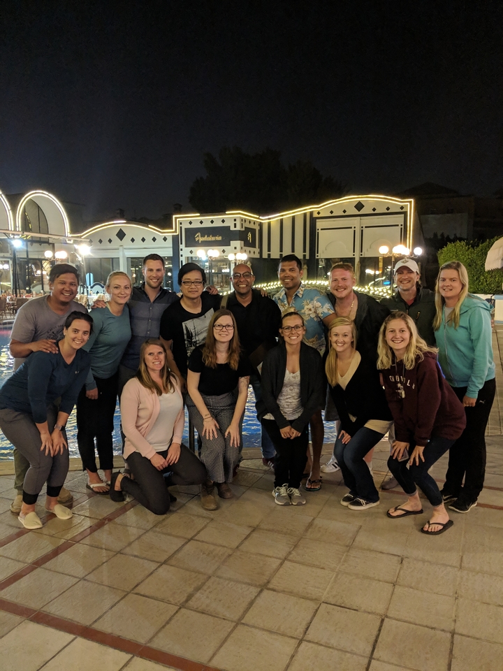 Groupe de personnes posant ensemble la nuit près d'une piscine.