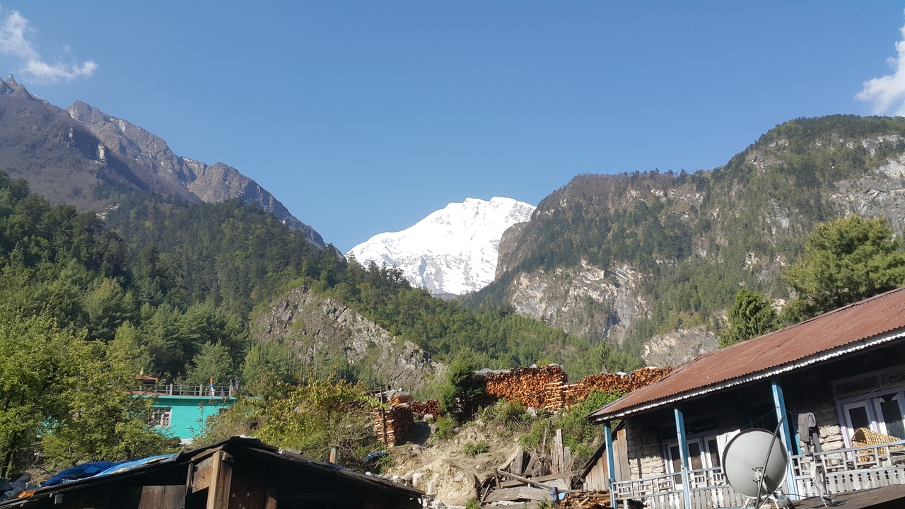 Paysage de montagne avec des maisons et un sommet enneigé en arrière-plan.