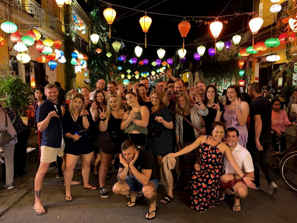 Groupe de personnes célébrant sous des lanternes colorées.