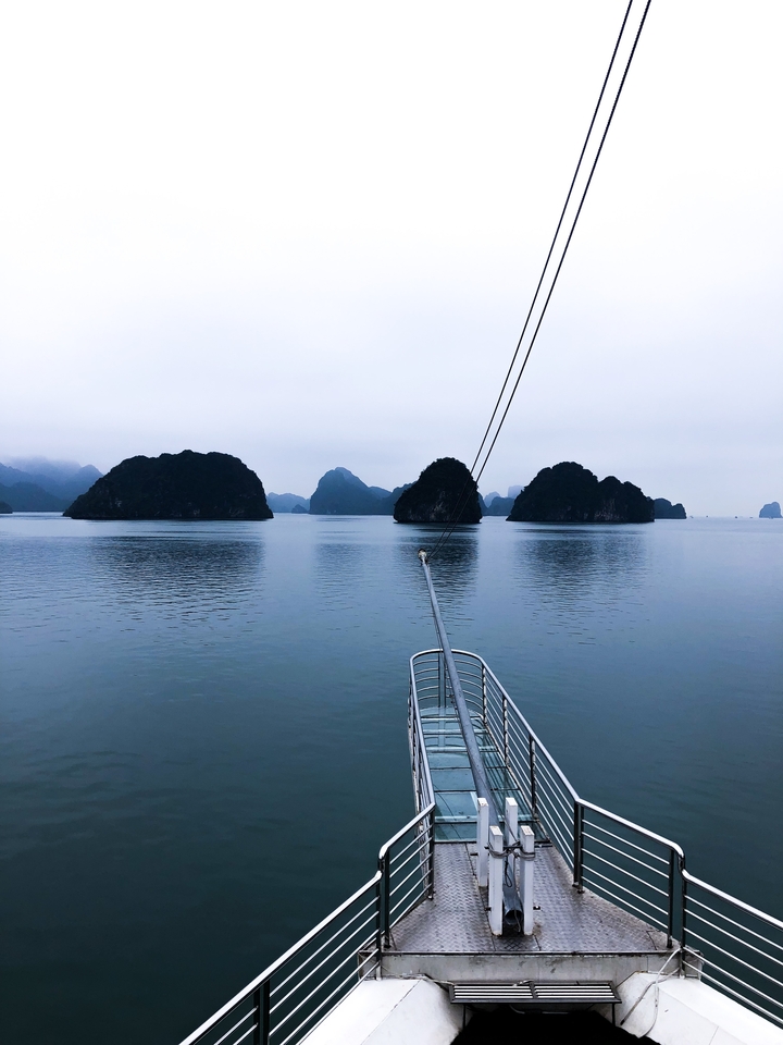 Boat on calm water with distant islands and fog in the background.
