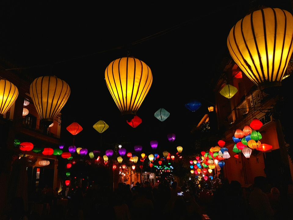 Des lanternes colorées suspendues dans la nuit.