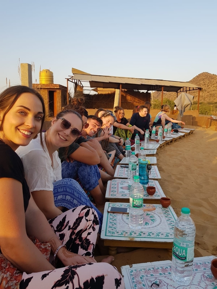 Groupe de personnes assises à des tables en plein air dans le désert.