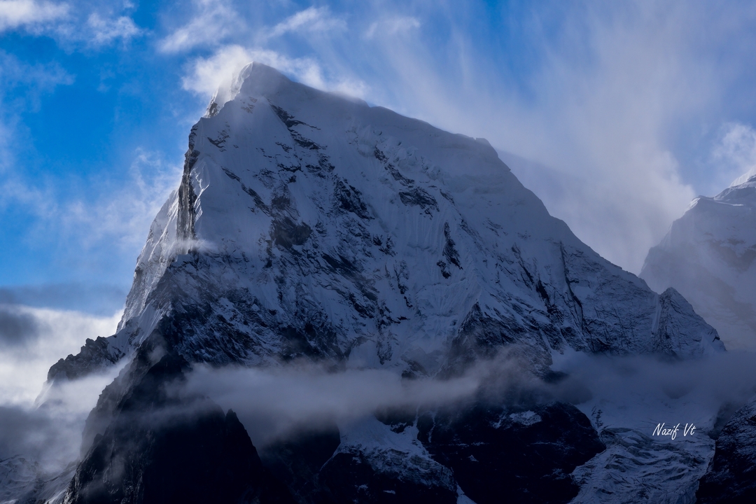 Sommet d'une montagne enneigée avec des nuages.