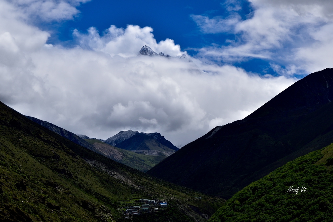 Paysage de montagne avec des sommets nuageux et des vallées.