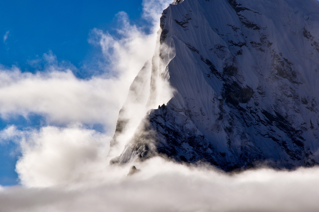 Montagne ensoleillée partiellement couverte de nuages.