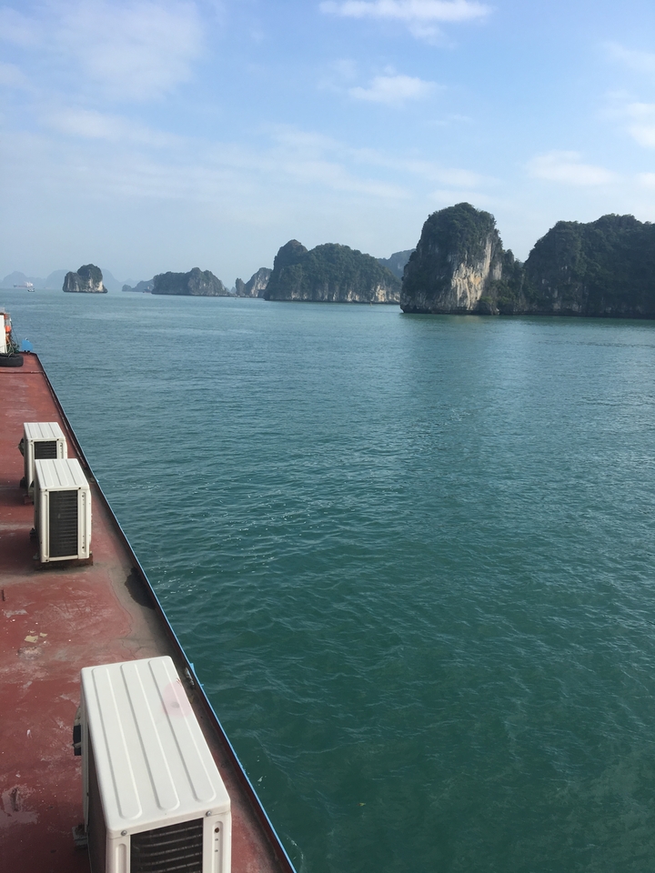 Boat on calm water with limestone cliffs.