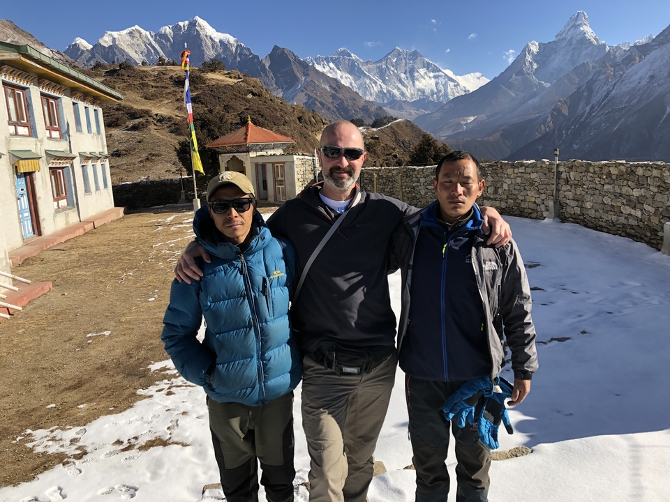 Trois personnes qui posent dans une cour avec des montagnes en arrière-plan.