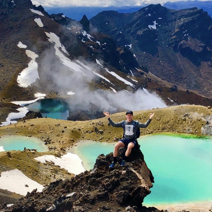 Person posing with steaming lakes in a volcanic area.