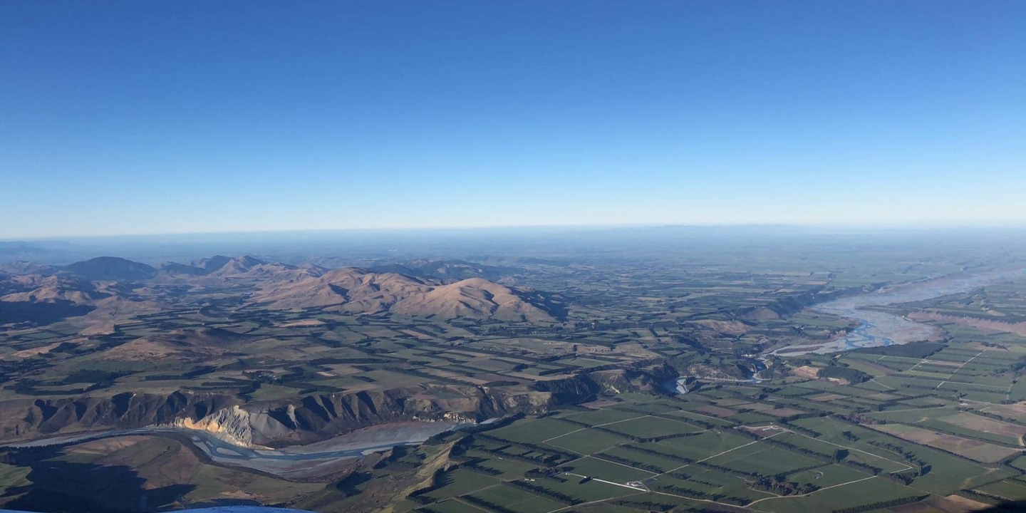 Vue aérienne d'une rivière et de terres agricoles avec des montagnes.