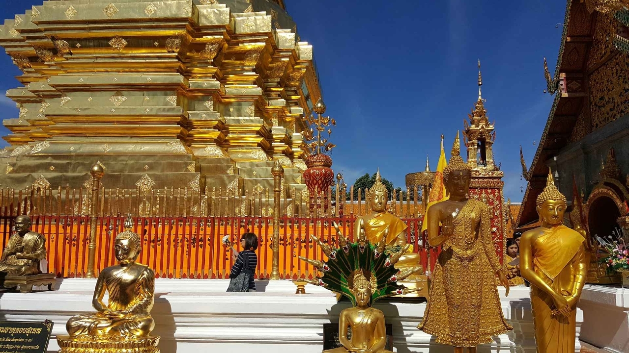 Des statues dorées et un complexe de temples sous un ciel bleu.