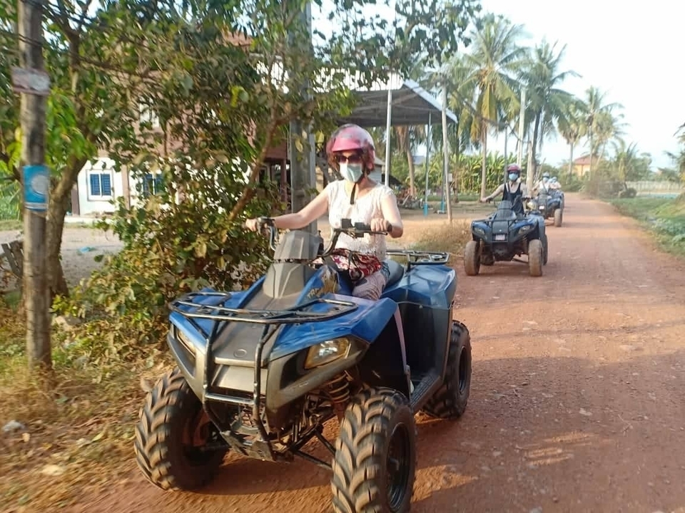 Des gens qui font du quad sur une route rurale poussiéreuse.