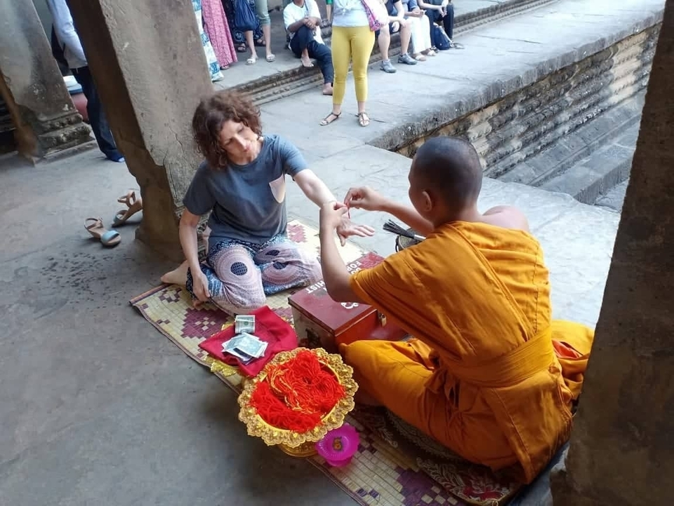 Un moine bénissant une femme à l'intérieur d'un complexe de temples anciens.