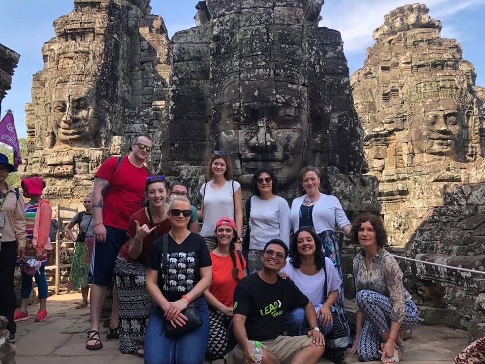 Groupe de touristes posant devant d'anciens visages de pierre.